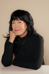 Photo of author Eileen Lee sitting a table smiling at the camera